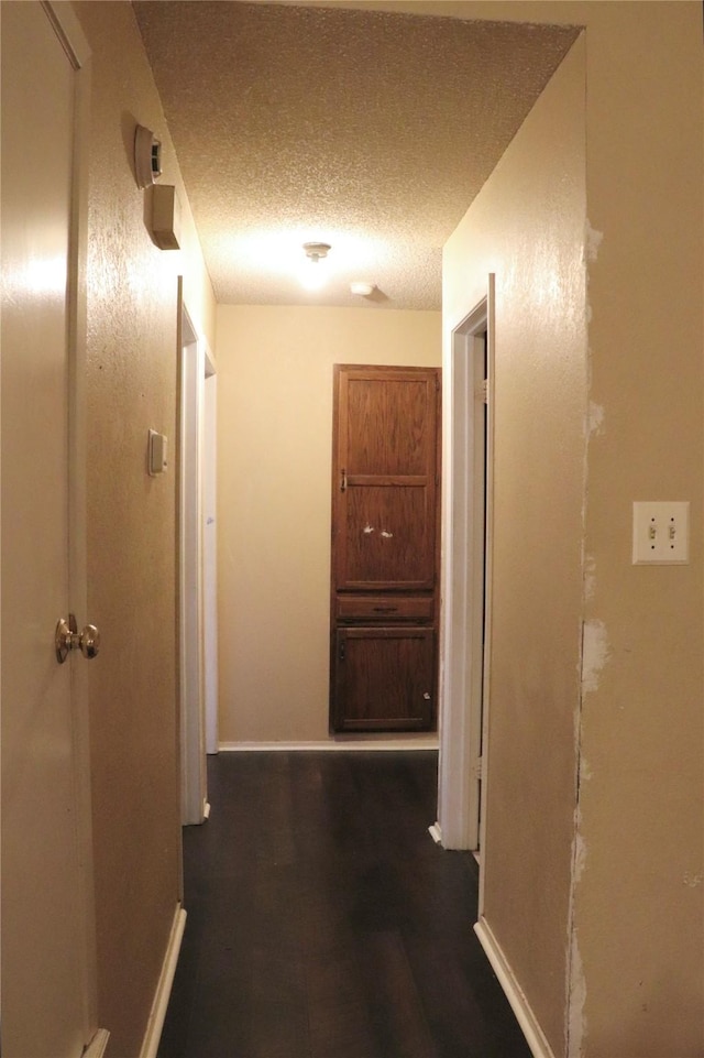 hall with dark hardwood / wood-style floors and a textured ceiling