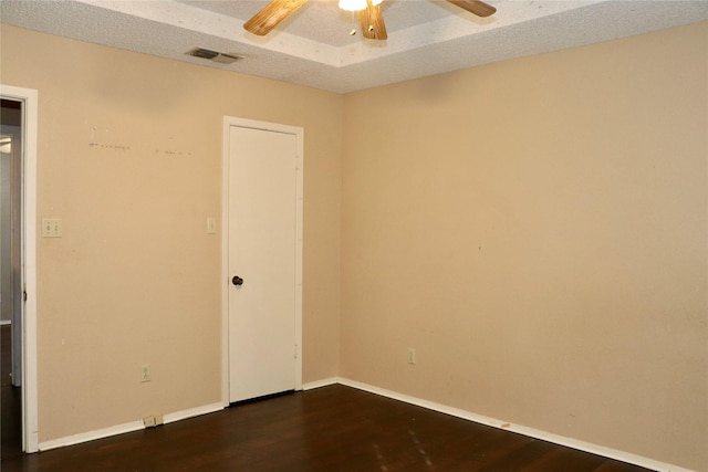 unfurnished room with a textured ceiling, dark wood-type flooring, and ceiling fan