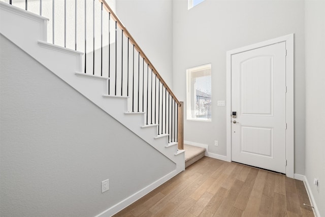 entrance foyer with light wood-type flooring, a towering ceiling, and a wealth of natural light