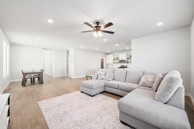 living room with light wood-type flooring and ceiling fan