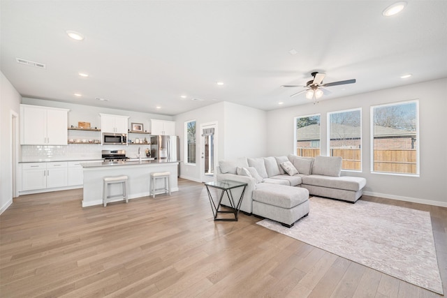 living room featuring light hardwood / wood-style floors, sink, and ceiling fan