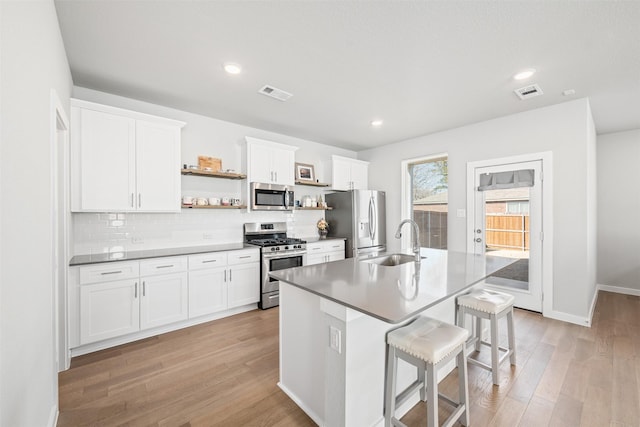 kitchen with sink, white cabinets, a kitchen bar, an island with sink, and stainless steel appliances