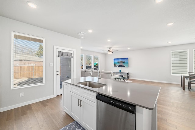 kitchen featuring white cabinets, an island with sink, sink, stainless steel dishwasher, and light hardwood / wood-style flooring