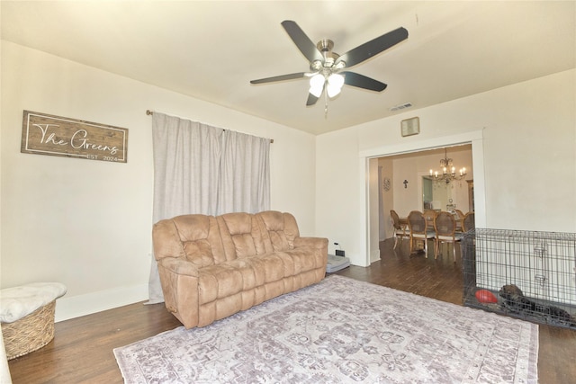 living room with ceiling fan with notable chandelier and dark hardwood / wood-style floors