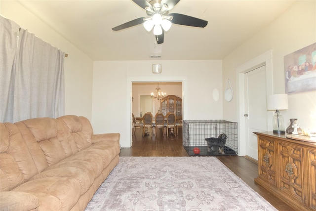 living room with ceiling fan with notable chandelier and dark hardwood / wood-style floors