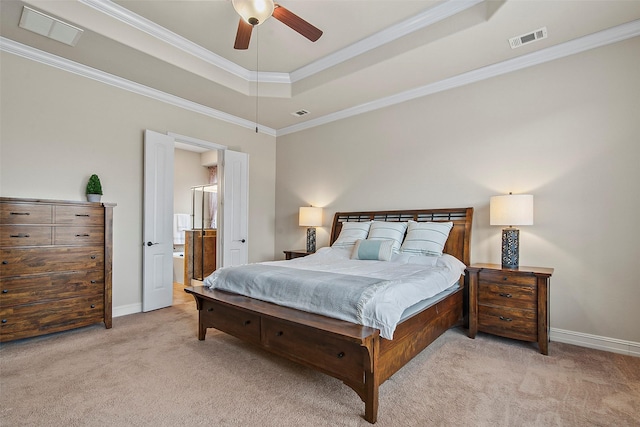 bedroom featuring connected bathroom, light carpet, ornamental molding, ceiling fan, and a tray ceiling