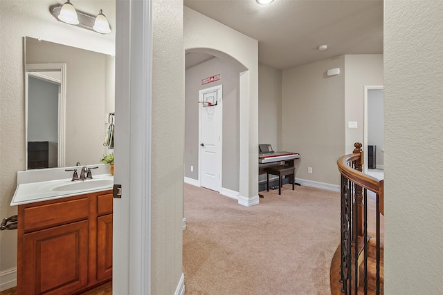 corridor with sink and light colored carpet