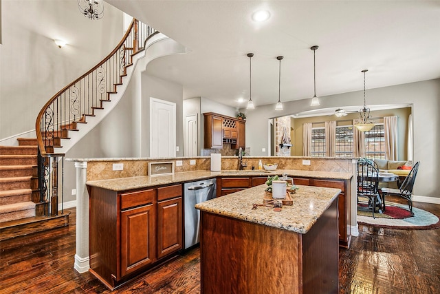 kitchen with hanging light fixtures, stainless steel dishwasher, sink, kitchen peninsula, and dark wood-type flooring