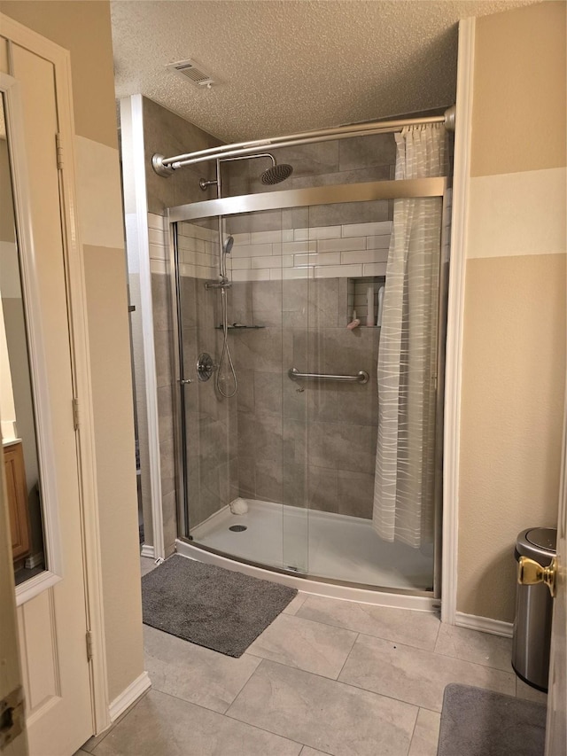 bathroom featuring a shower with door, a textured ceiling, and tile patterned floors