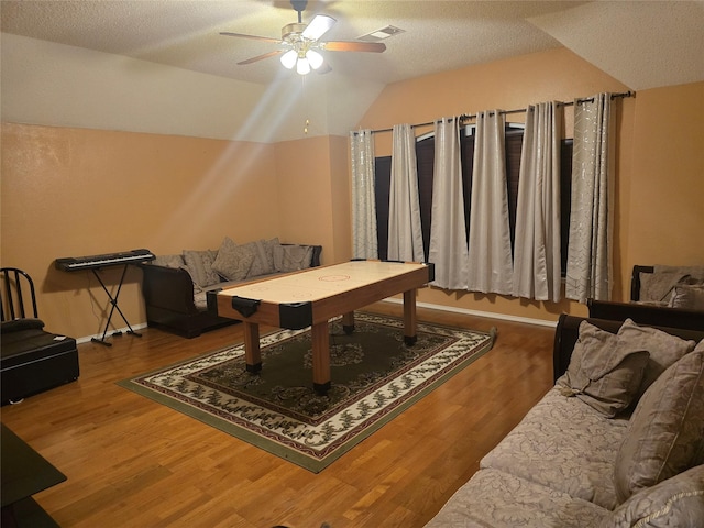 game room with ceiling fan, hardwood / wood-style floors, lofted ceiling, and a textured ceiling