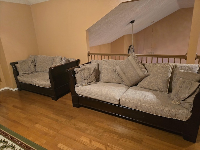 living room featuring wood-type flooring, a textured ceiling, and vaulted ceiling