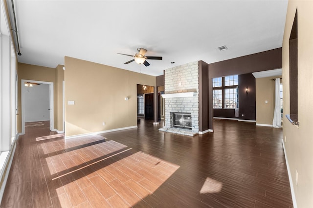 unfurnished living room featuring a brick fireplace, dark hardwood / wood-style floors, and ceiling fan