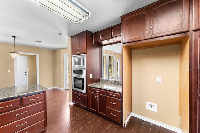 kitchen with appliances with stainless steel finishes, hanging light fixtures, dark hardwood / wood-style floors, dark stone counters, and a chandelier