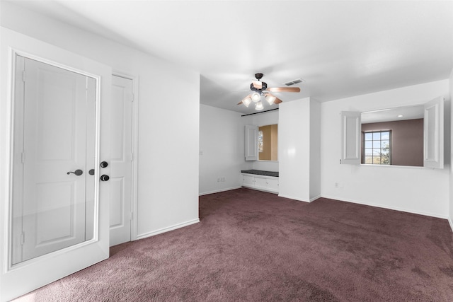 unfurnished room with ceiling fan and dark carpet