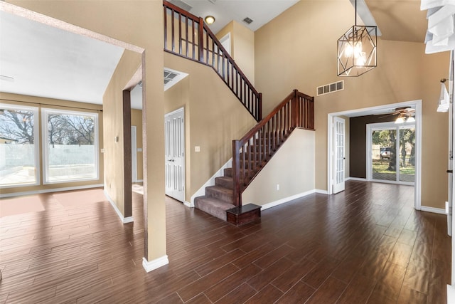 entrance foyer featuring a towering ceiling and dark wood-type flooring