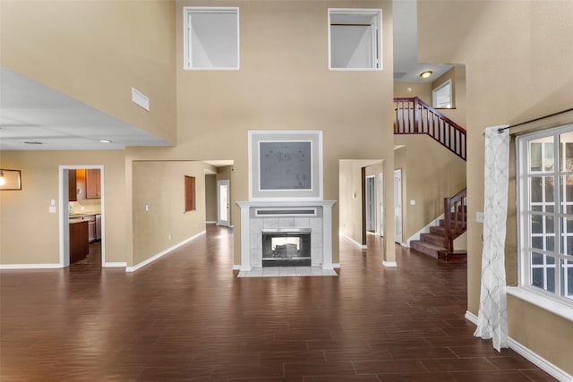 unfurnished living room featuring a tiled fireplace and a high ceiling