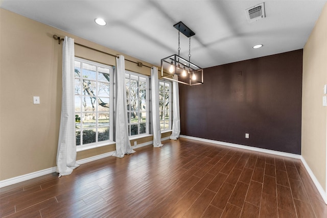 unfurnished dining area featuring dark wood-type flooring, a healthy amount of sunlight, and decorative columns