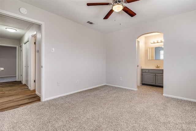 unfurnished bedroom with sink, ceiling fan, light carpet, and ensuite bath