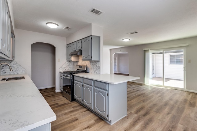 kitchen with tasteful backsplash, sink, gray cabinets, kitchen peninsula, and gas range