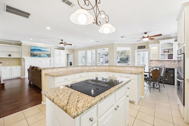 kitchen featuring hanging light fixtures, black electric cooktop, white cabinets, a kitchen island, and light tile patterned flooring