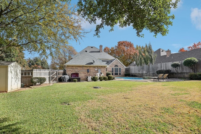 view of yard with a fenced in pool and a storage unit