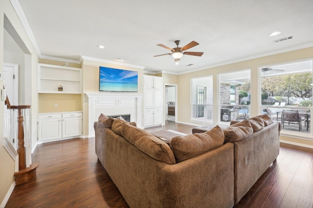 living room featuring built in shelves, dark hardwood / wood-style floors, ceiling fan, and ornamental molding