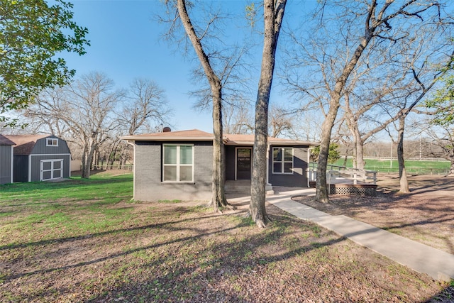 view of front of property featuring a deck, a storage shed, and a front yard