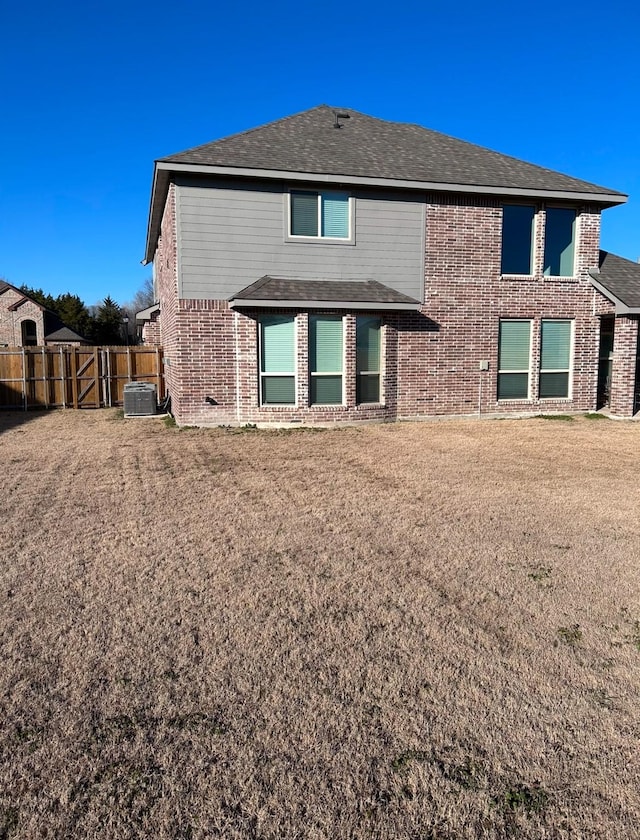 back of property featuring central air condition unit and a lawn