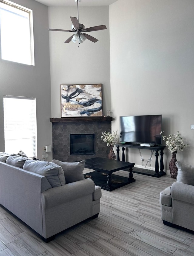 living room featuring wood-type flooring, a healthy amount of sunlight, a fireplace, and ceiling fan