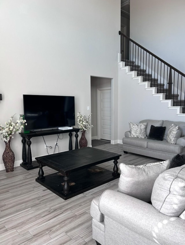 living room featuring light wood-type flooring and a high ceiling