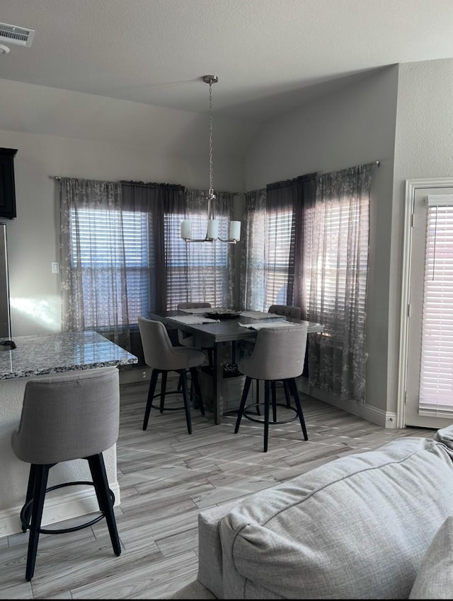 dining area featuring light hardwood / wood-style flooring, lofted ceiling, and an inviting chandelier