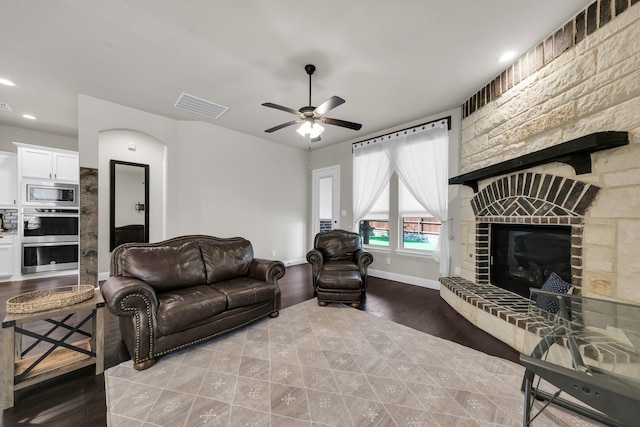 living room featuring ceiling fan and a stone fireplace