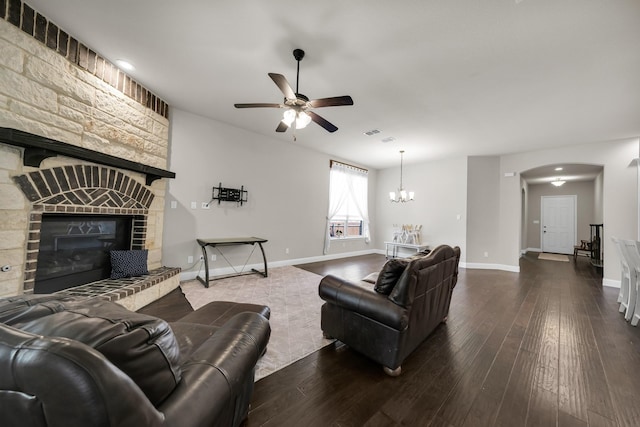 living room with hardwood / wood-style flooring, a stone fireplace, and ceiling fan with notable chandelier