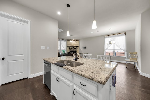 kitchen with a fireplace, stainless steel dishwasher, sink, white cabinets, and an island with sink