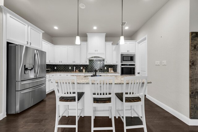 kitchen with decorative light fixtures, a center island with sink, white cabinetry, and appliances with stainless steel finishes