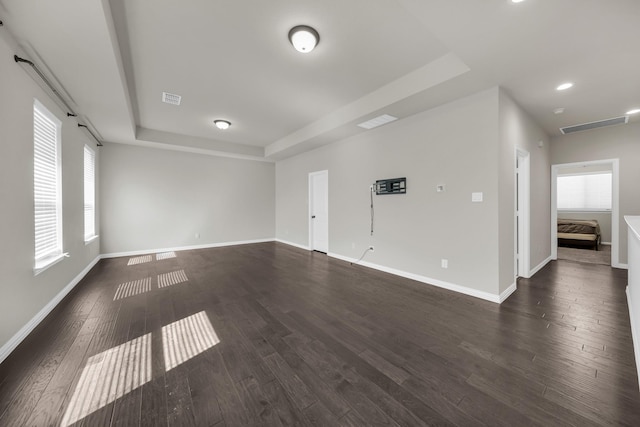 empty room featuring dark hardwood / wood-style floors and a tray ceiling