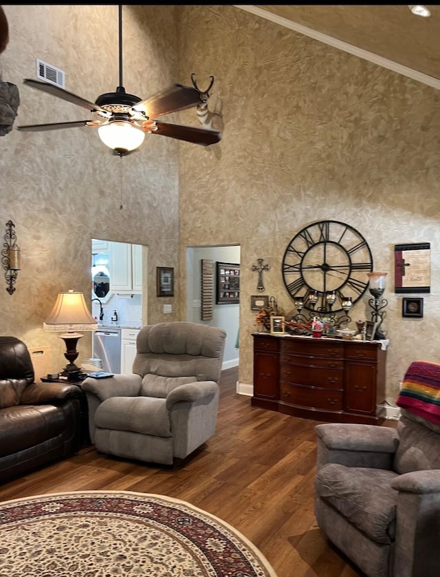 living room with ceiling fan, dark hardwood / wood-style floors, crown molding, and a towering ceiling