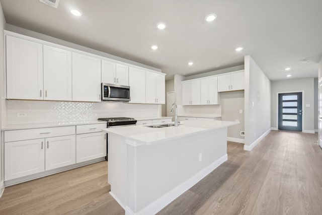 kitchen with white cabinetry, sink, stainless steel appliances, and a center island with sink