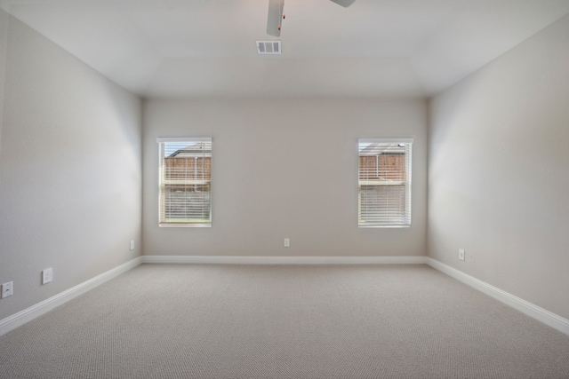 carpeted spare room with ceiling fan and plenty of natural light