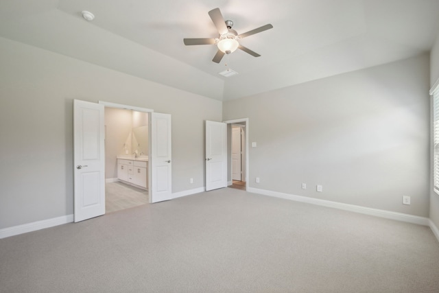 unfurnished bedroom featuring ceiling fan, connected bathroom, vaulted ceiling, and light carpet