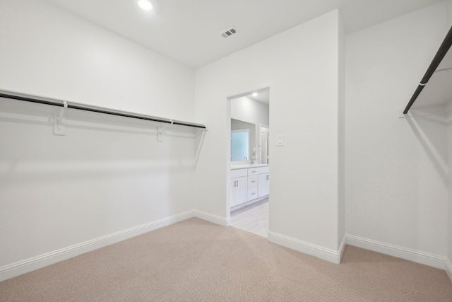 walk in closet featuring light carpet