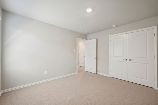 unfurnished bedroom featuring light carpet and a closet