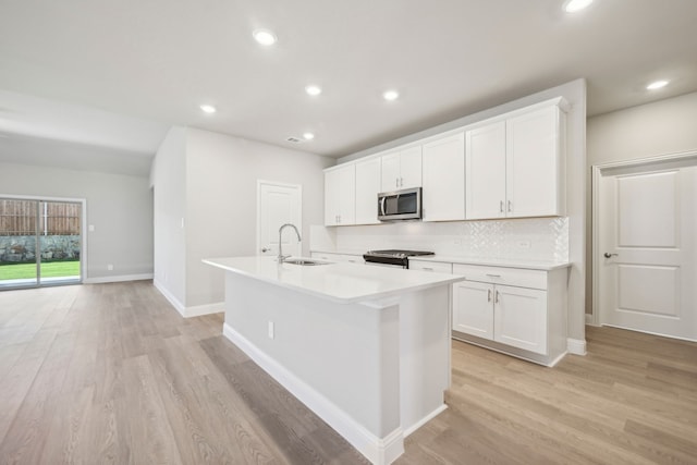 kitchen with white cabinetry, light hardwood / wood-style floors, sink, and a center island with sink