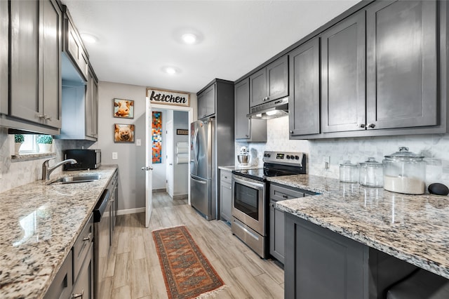 kitchen featuring light hardwood / wood-style flooring, sink, light stone counters, decorative backsplash, and stainless steel appliances