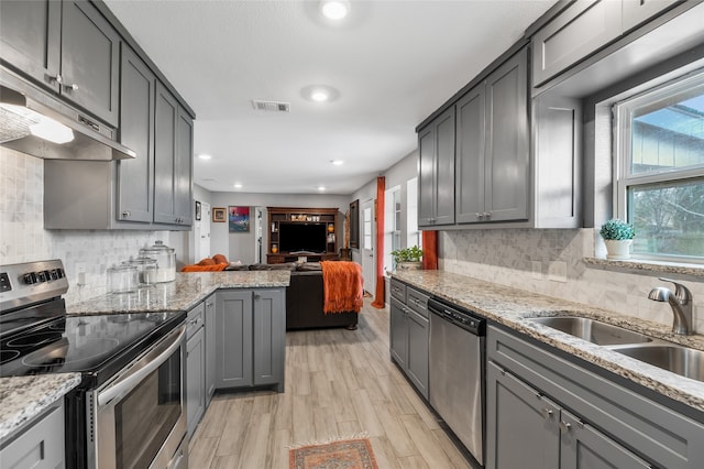 kitchen with sink, appliances with stainless steel finishes, gray cabinetry, and light wood-type flooring