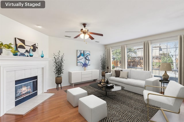 living room with a fireplace, light hardwood / wood-style flooring, and ceiling fan