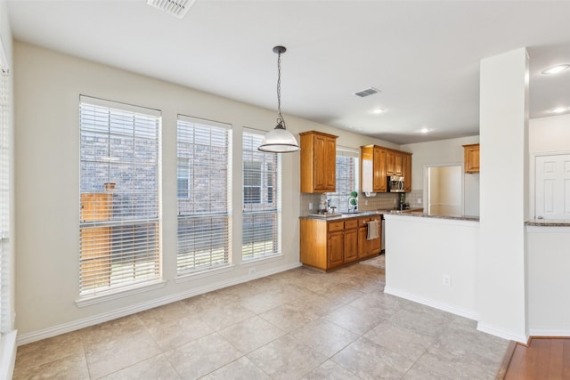 kitchen featuring sink, decorative backsplash, hanging light fixtures, and light tile patterned floors