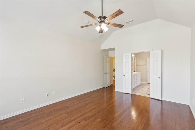 unfurnished bedroom featuring ceiling fan, dark hardwood / wood-style floors, vaulted ceiling, and ensuite bath