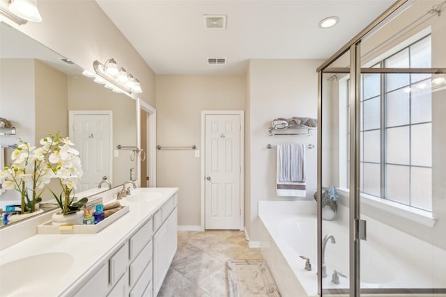 bathroom featuring a relaxing tiled tub, vanity, and tile patterned flooring