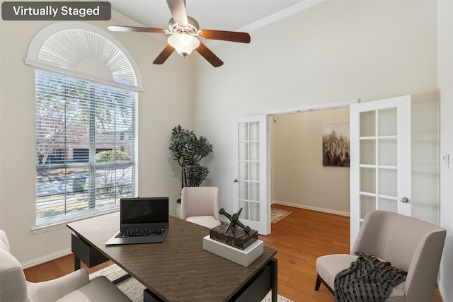 office featuring french doors, ceiling fan, wood-type flooring, and a towering ceiling